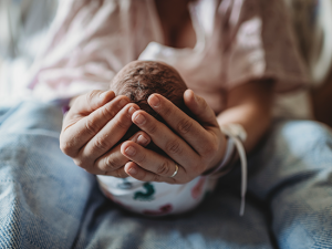 Women's hands holding an infant