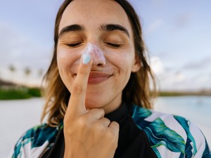 Female smiling and placing sunscreen on her nose