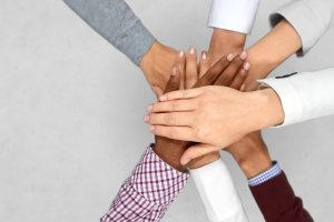 Hands overlapping each other of all different races to represent Diversity, Equity & Inclusion