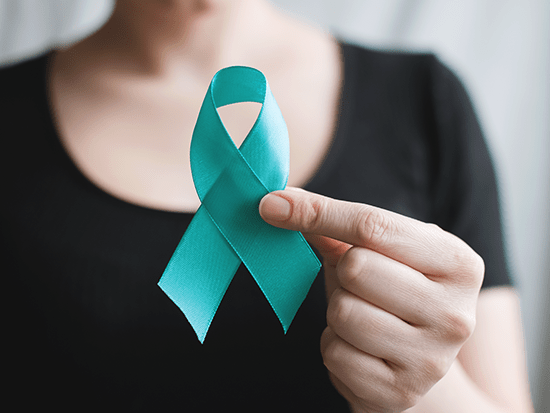 Caucasian female holding up a teal ribbon for Ovarian Cancer