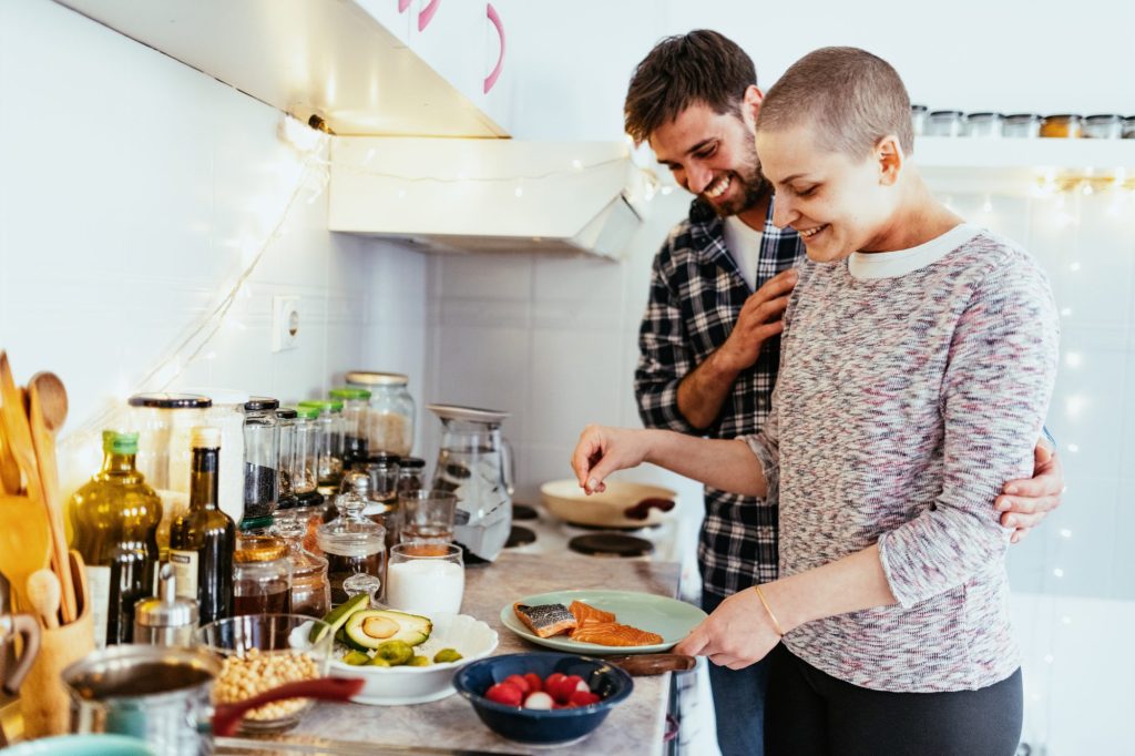 Woman with cancer cooking and smiling with her boyfriend at home