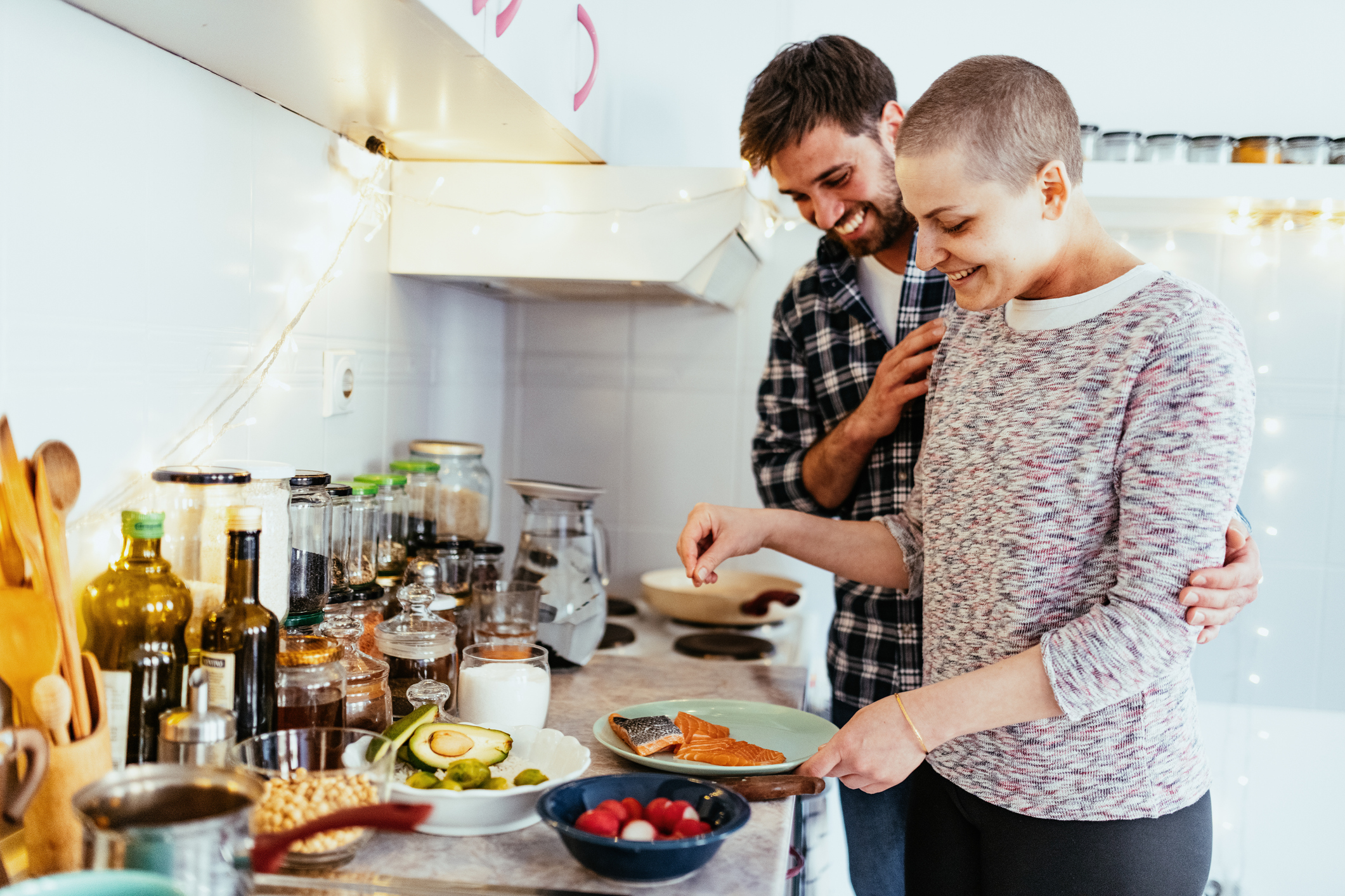 Woman with cancer cooking and smiling with her boyfriend at home