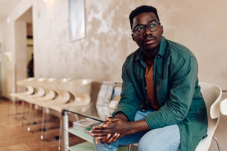 Worried African American young man sitting in a chair in a waiting room