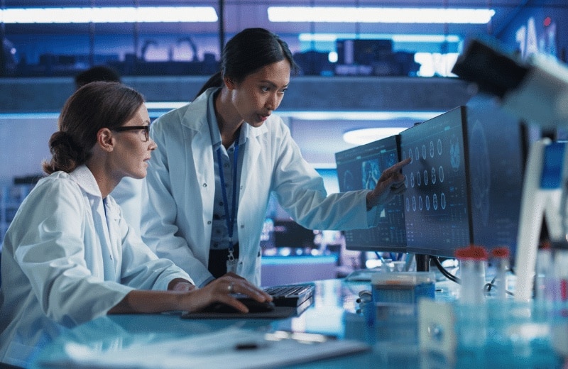 Two medical experts looking at a computer and discussing the information on the screen