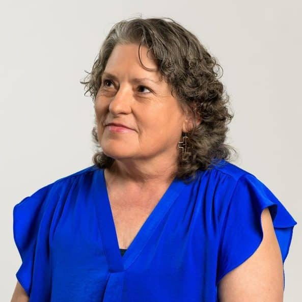 A adult woman – Lisa Williams – in a blue dress looking out into the distance.