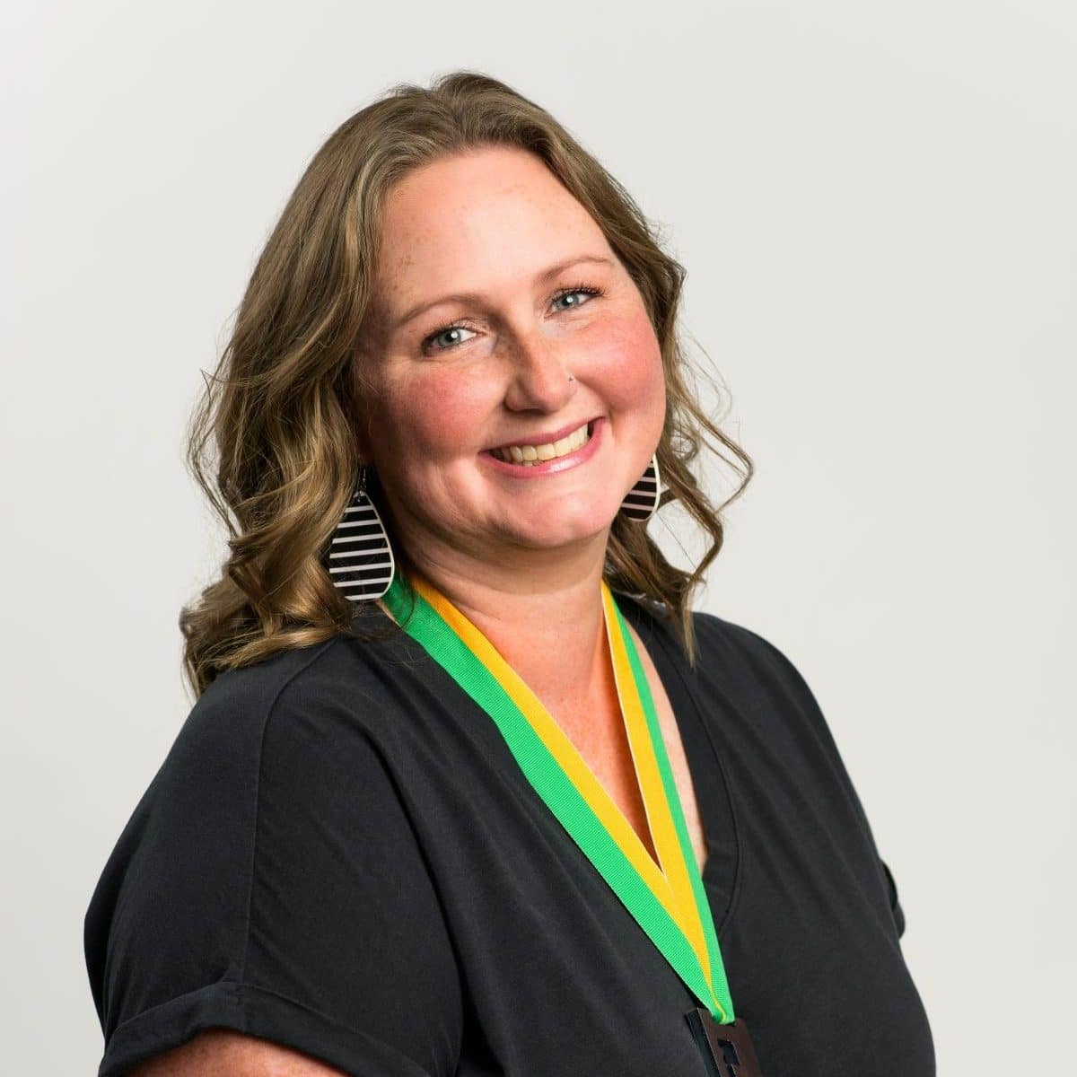 An adult woman in a black dress - Becki Quinn - wearing the "Fe" Iron Strong medal.
