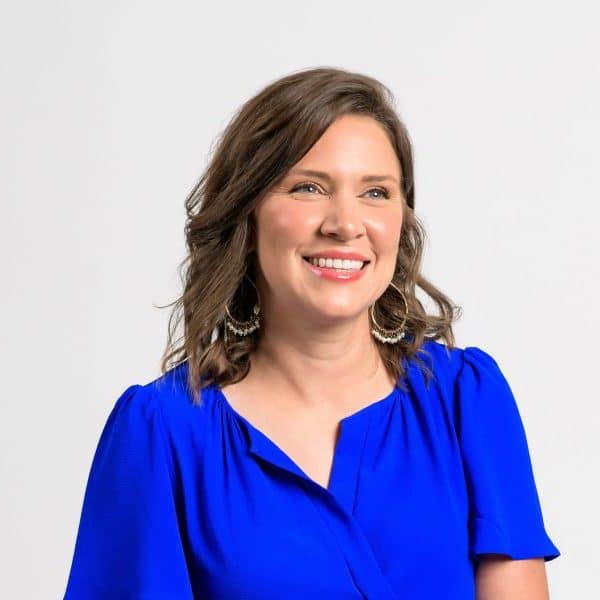 A woman – Stephanie King – in a bright blue dress smiling past the camera.