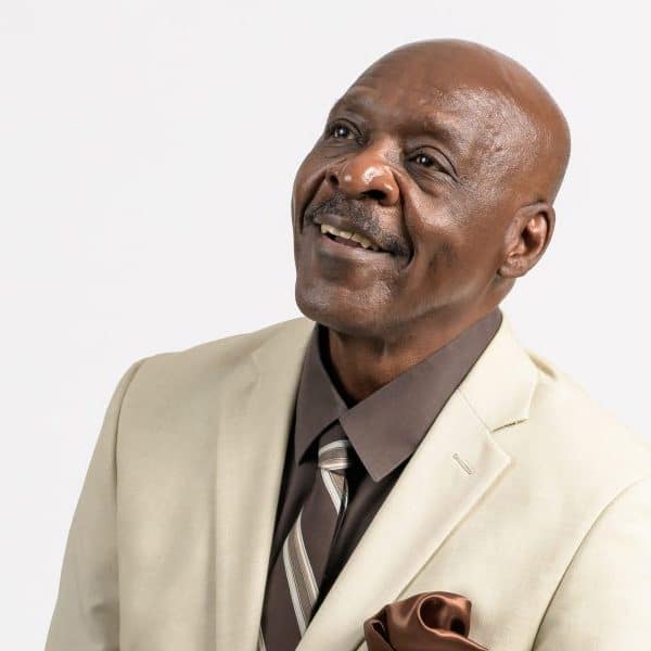 A photo of an older Black man – Albert Isaac – with a moustache in a tan suit.