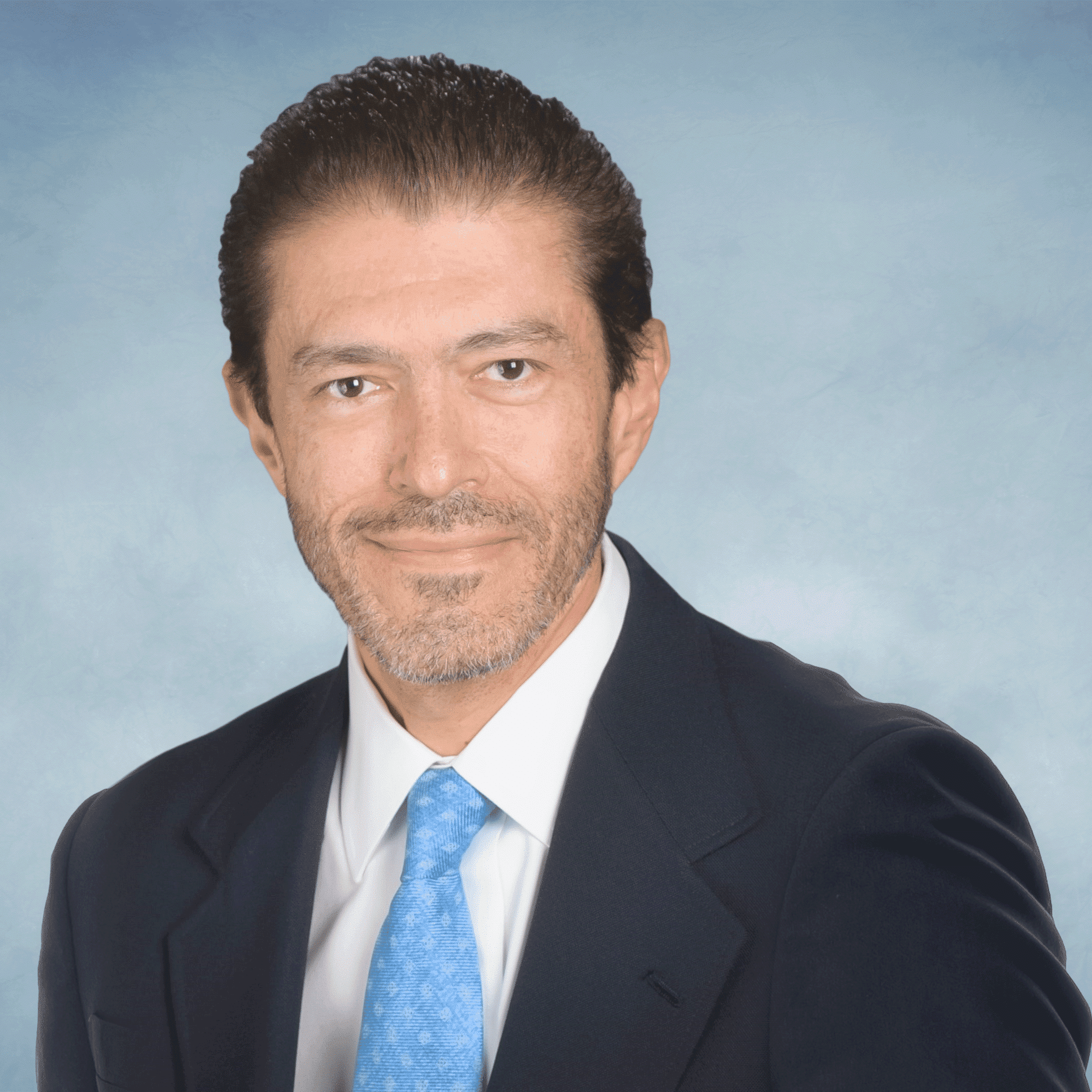 A headshot of a man in blue suit with a light blue tie - Jorge Cortez, M.D.