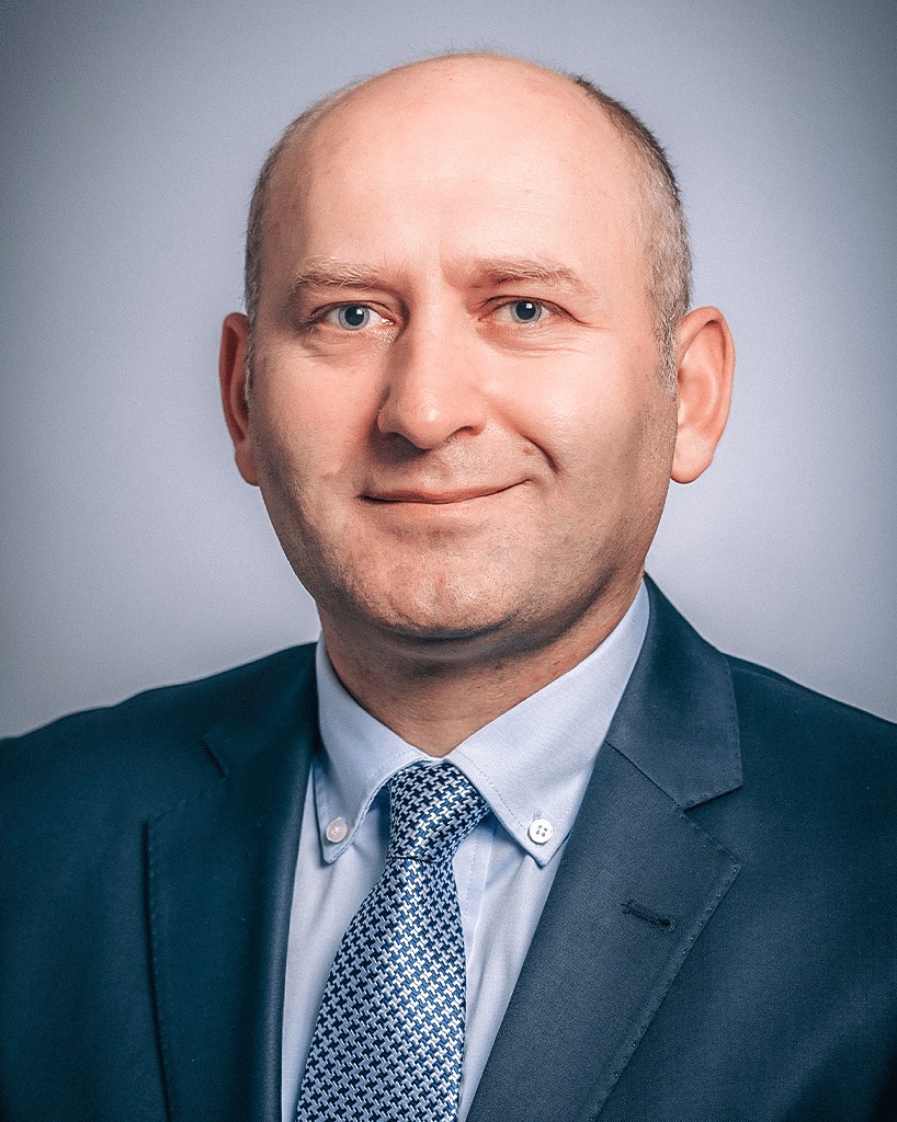 A headshot of a scientist in a blue suit and a decorative blue tie; Mehmet Akce, M.D.