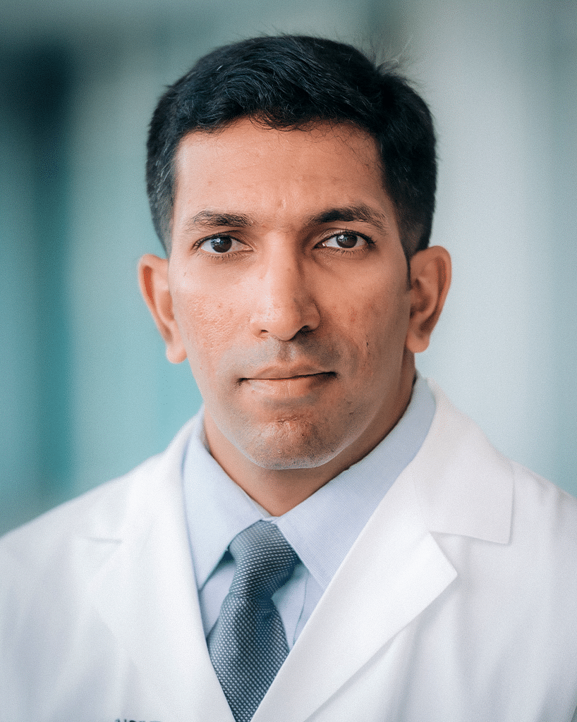 A headshot of a doctor outdoors in a white labcoat, a dress shirt, and a blue tie; Pankit Vachhani, M.D.