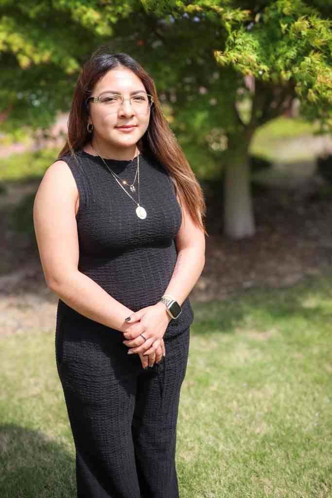 Karla Lopez, an Iron Strong award winner, standing outside the Women and Children's Center in the garden.