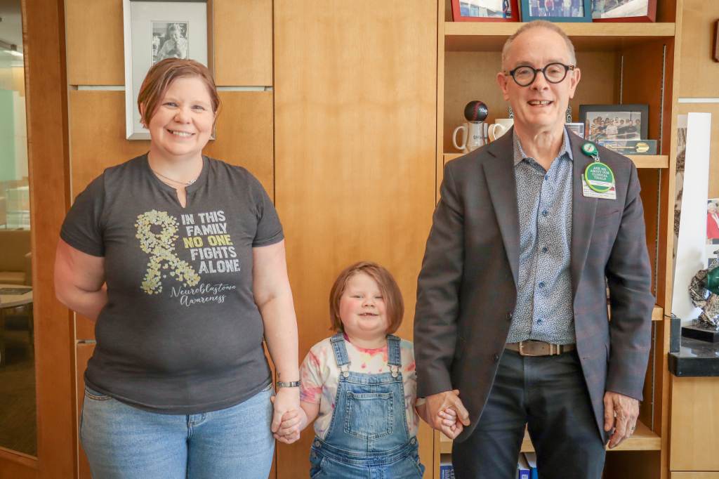 Iron Strong awardee Piper Diamond stands smiling, holding hands with her mother, Rhonda Diamond, and the director of the UAB O'Neal Cancer Center, Barry Sleckman, M.D., Ph.D.