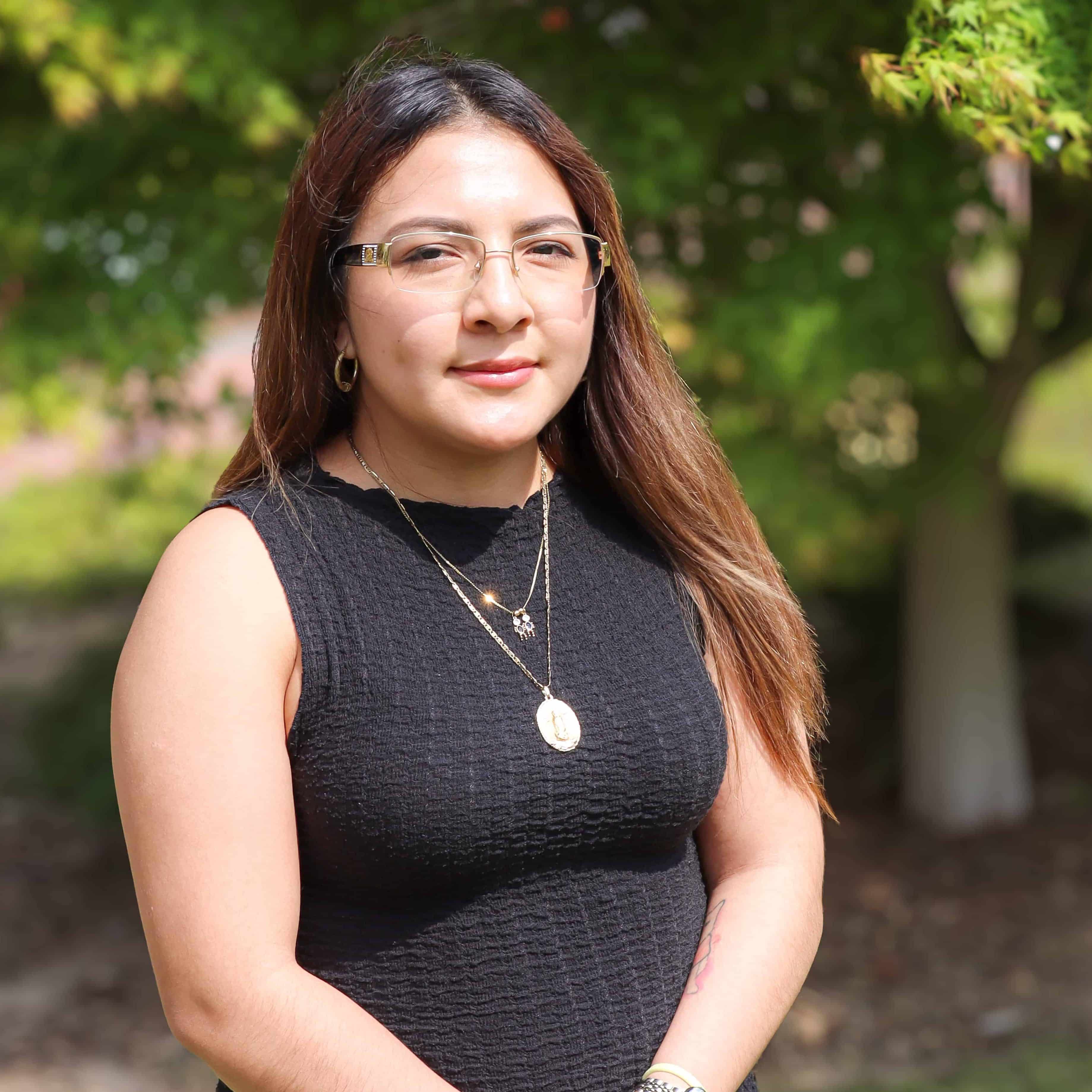 Karla Lopez, an Iron Strong award winner, standing outside the Women and Children's Center in the garden.