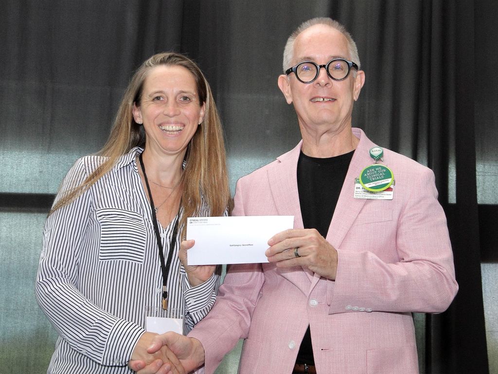 Andrea Comba, Ph.D., receives an award at the 2026 O'Neal Research Retreat on behalf of Dilani Patel.