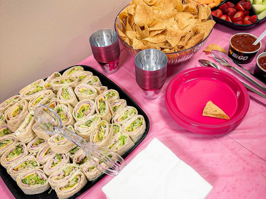 Refreshments at the 2026 Pink Party, consisting of rolled up sandwiches, chips, and fruit.